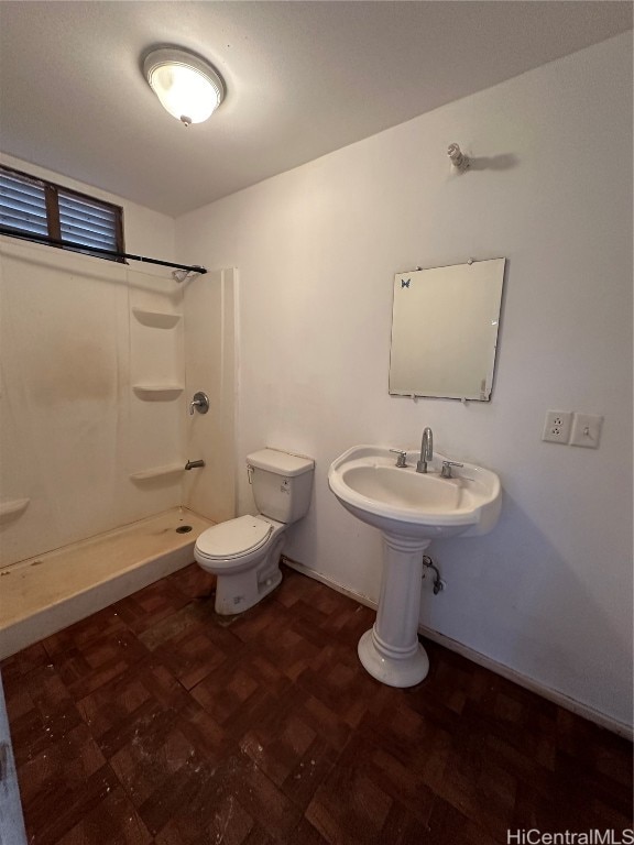 bathroom with walk in shower, sink, and toilet