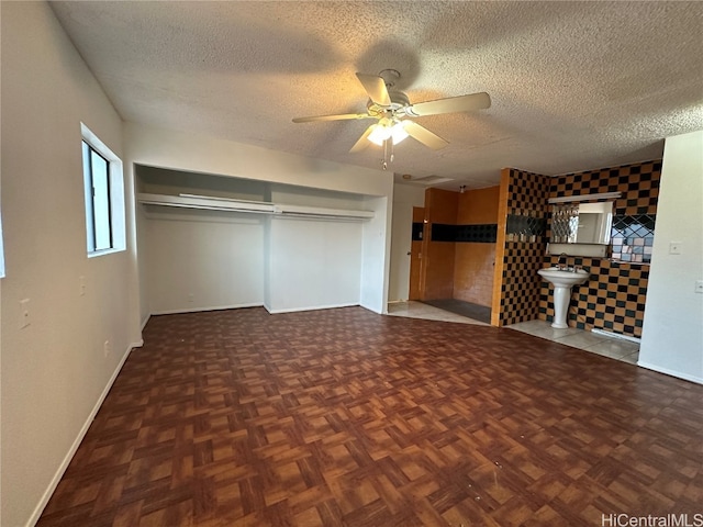 interior space with dark parquet flooring, sink, a textured ceiling, and ceiling fan