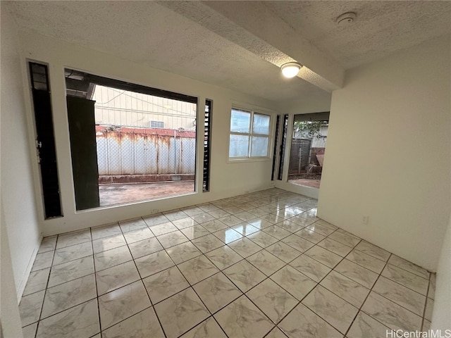 unfurnished room with a textured ceiling and light tile patterned flooring