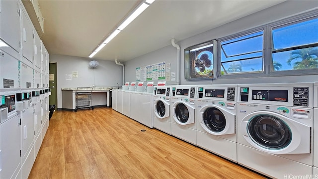 laundry area featuring light hardwood / wood-style flooring, stacked washer / drying machine, and washing machine and clothes dryer