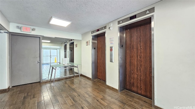 hallway featuring elevator, dark hardwood / wood-style floors, and a textured ceiling