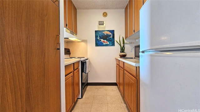 kitchen with a textured ceiling, white fridge, black electric range, and sink