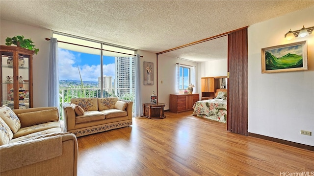 living room featuring light wood-type flooring, plenty of natural light, a textured ceiling, and floor to ceiling windows