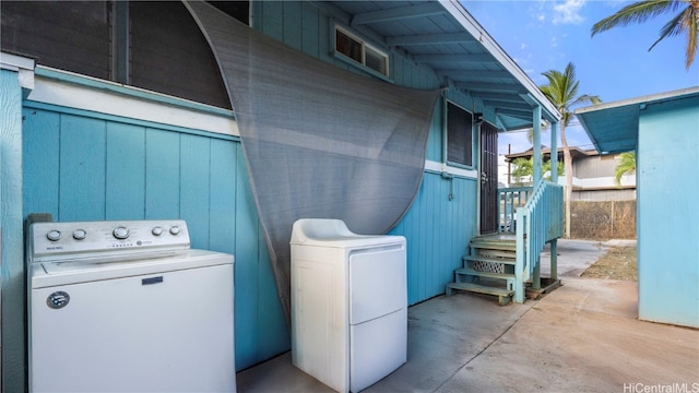 laundry area with wooden walls and washing machine and clothes dryer