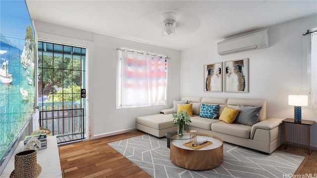 living room featuring hardwood / wood-style floors, a wall unit AC, and ceiling fan