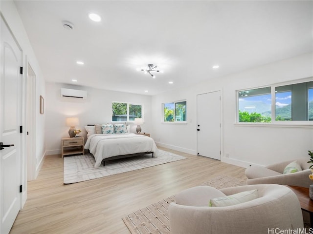 bedroom featuring light hardwood / wood-style flooring and an AC wall unit