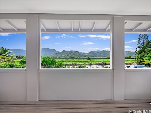 interior space featuring beamed ceiling, a water and mountain view, hardwood / wood-style flooring, and a healthy amount of sunlight