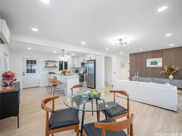 dining area featuring light wood-type flooring and a wall unit AC