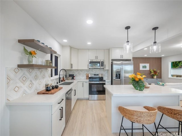 kitchen with appliances with stainless steel finishes, white cabinetry, hanging light fixtures, and sink