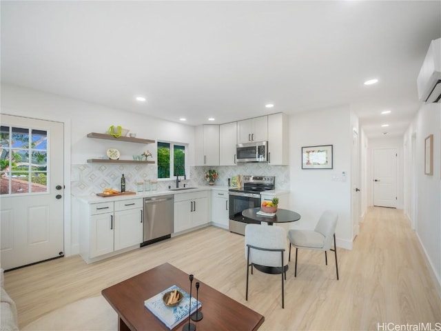 kitchen featuring sink, decorative backsplash, light wood-type flooring, appliances with stainless steel finishes, and white cabinetry