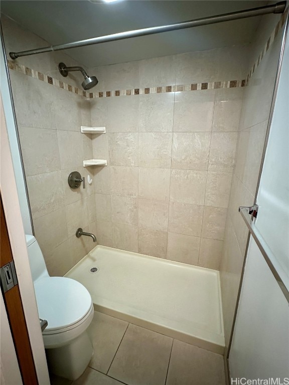 bathroom featuring tile patterned flooring, toilet, and tiled shower