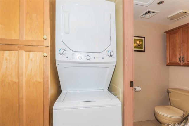 clothes washing area with tile patterned flooring and stacked washer / dryer