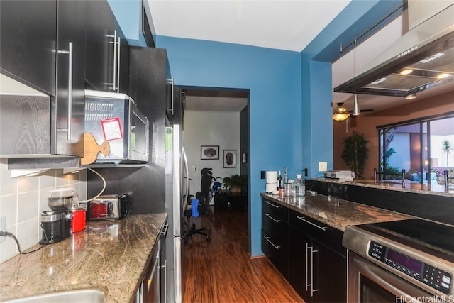 kitchen with dark hardwood / wood-style floors, stainless steel range oven, exhaust hood, and dark stone counters