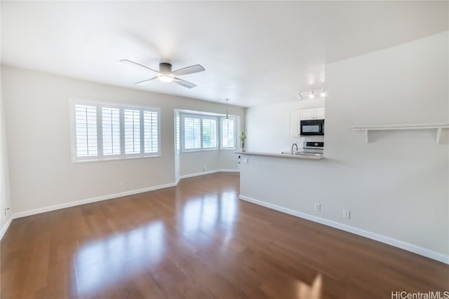 unfurnished living room featuring dark hardwood / wood-style floors, ceiling fan, and sink