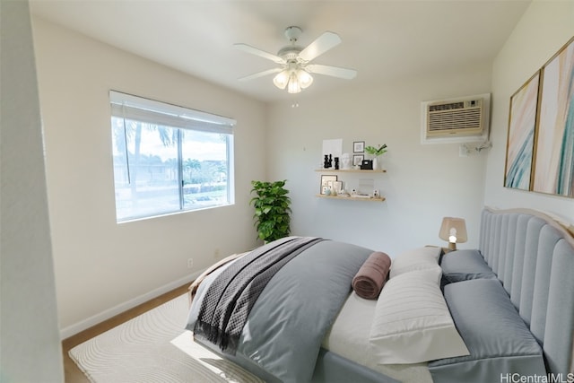 bedroom featuring a wall mounted AC, wood-type flooring, and ceiling fan