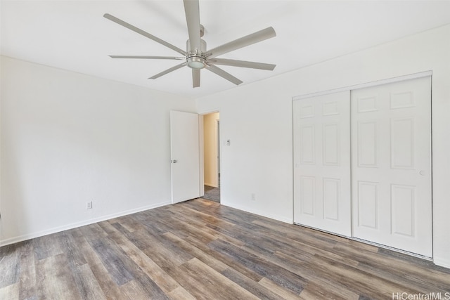 unfurnished bedroom with dark wood-type flooring, ceiling fan, and a closet