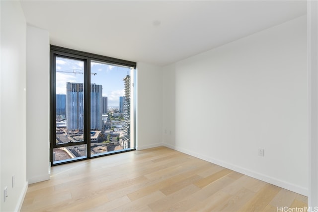 unfurnished room with a wall of windows and light wood-type flooring