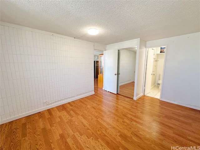 spare room with light hardwood / wood-style floors and a textured ceiling