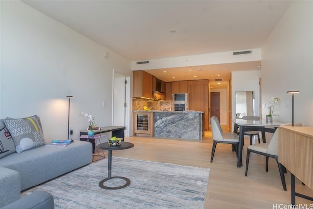 living room with beverage cooler and light hardwood / wood-style floors