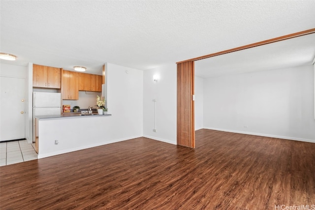 unfurnished living room featuring wood-type flooring and a textured ceiling