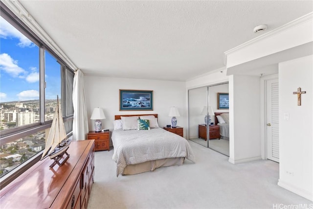 bedroom featuring light colored carpet, a textured ceiling, and a closet