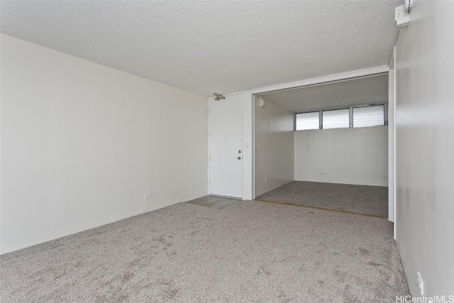 empty room with a textured ceiling and light carpet