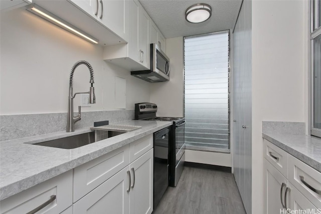 kitchen with sink, light wood-type flooring, stainless steel appliances, a textured ceiling, and white cabinets