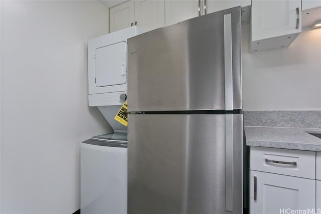 clothes washing area with stacked washing maching and dryer