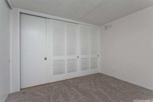 unfurnished bedroom featuring a textured ceiling, a closet, and carpet