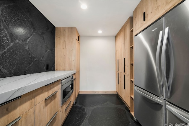 kitchen with appliances with stainless steel finishes, light brown cabinets, and light stone counters