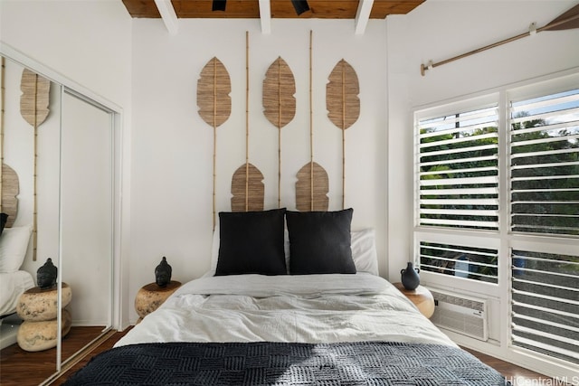 bedroom featuring beam ceiling, dark hardwood / wood-style floors, and a closet