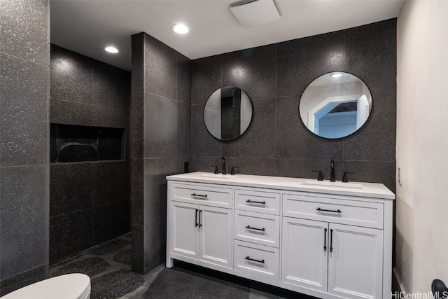 bathroom with vanity, toilet, tile walls, and walk in shower