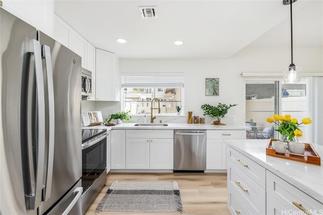 kitchen featuring pendant lighting, sink, white cabinetry, and stainless steel appliances