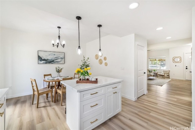 kitchen with a center island, white cabinets, pendant lighting, and light hardwood / wood-style floors