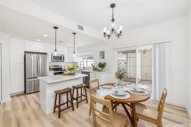 dining room featuring light hardwood / wood-style flooring, sink, and a chandelier