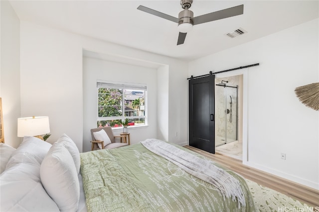 bedroom featuring a barn door, ceiling fan, and light hardwood / wood-style flooring