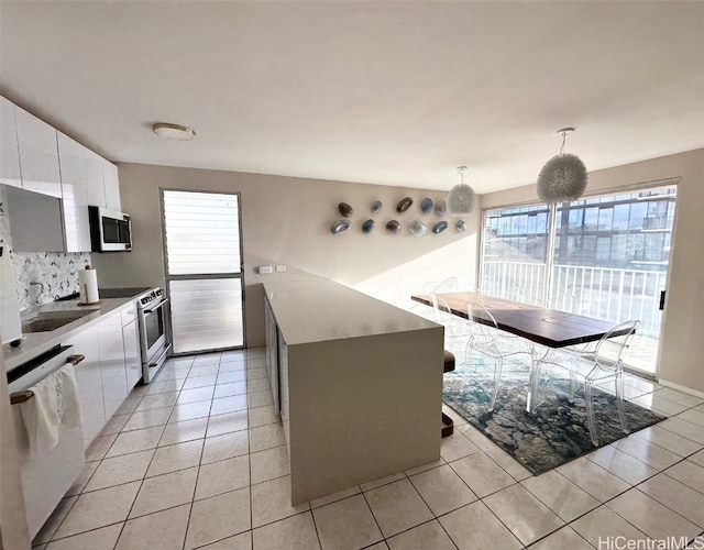 kitchen featuring white cabinetry, decorative light fixtures, sink, white appliances, and a center island