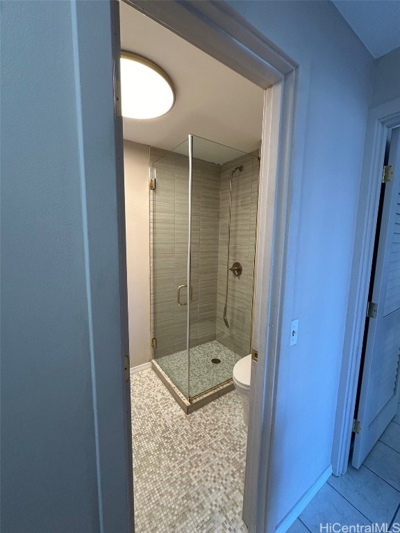 bathroom with tile patterned floors, toilet, and an enclosed shower