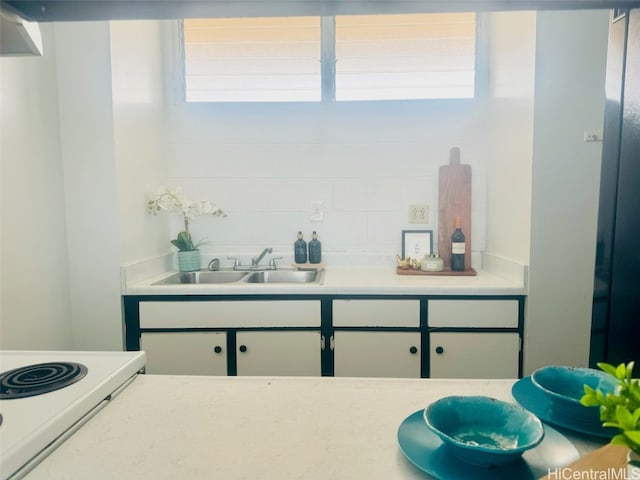 kitchen with a healthy amount of sunlight, white cabinetry, sink, and tasteful backsplash