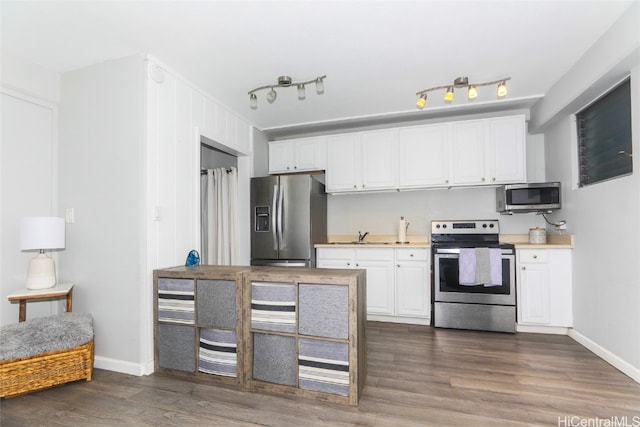 kitchen with appliances with stainless steel finishes, rail lighting, dark hardwood / wood-style floors, and white cabinets