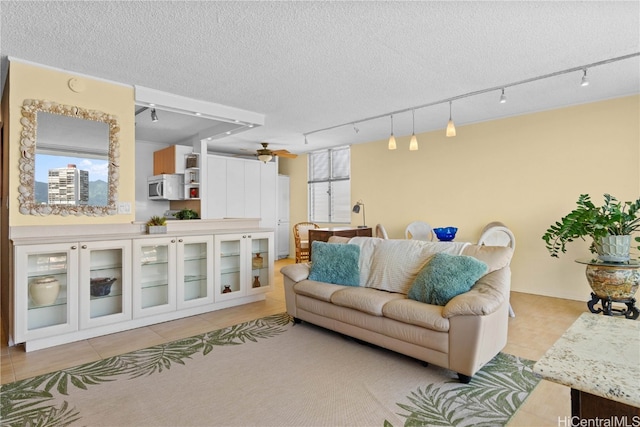 living room featuring light tile patterned floors, rail lighting, a textured ceiling, and ceiling fan