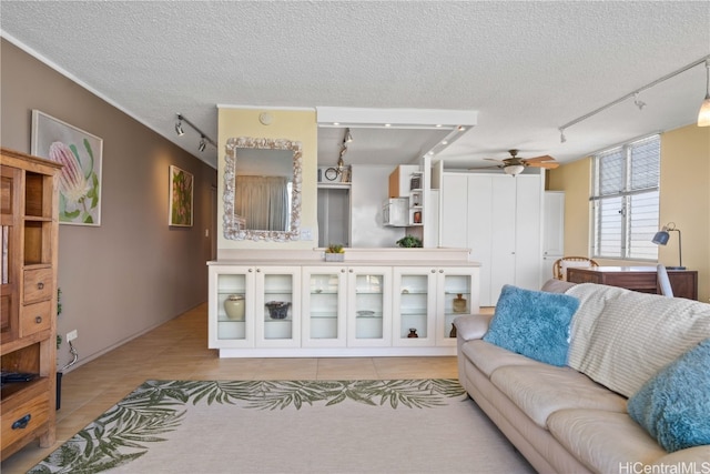 tiled living room with a textured ceiling, rail lighting, and ceiling fan