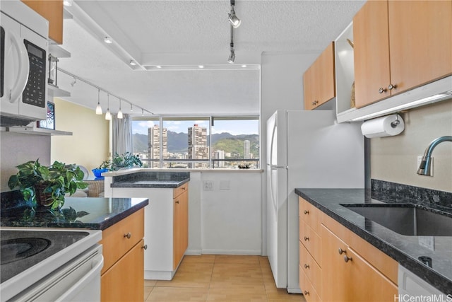 kitchen featuring sink, dark stone counters, a textured ceiling, white appliances, and light tile patterned flooring