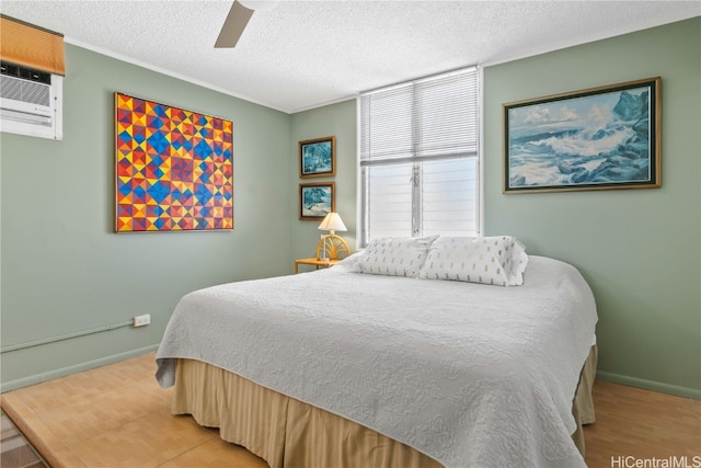 bedroom featuring an AC wall unit, ceiling fan, a textured ceiling, and hardwood / wood-style flooring