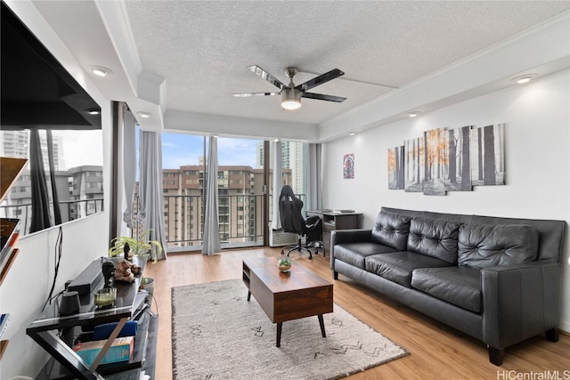 living room featuring light hardwood / wood-style floors, ceiling fan, a textured ceiling, and crown molding