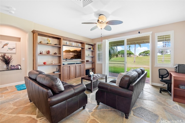 living room with built in features and ceiling fan