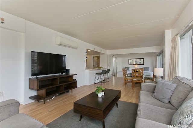 living room with light wood-type flooring and an AC wall unit