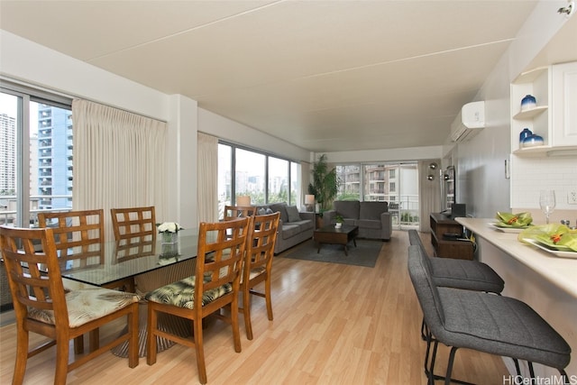 dining area featuring a wall mounted air conditioner and light hardwood / wood-style floors