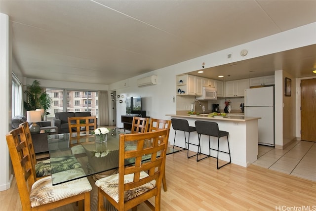 dining room with sink, a wall mounted AC, and light hardwood / wood-style flooring