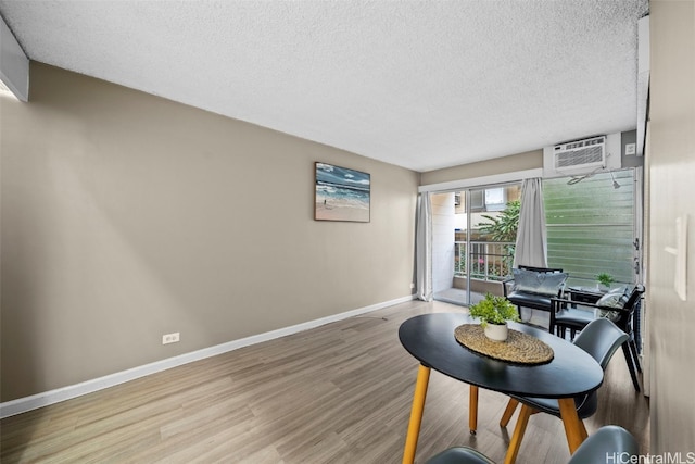 living area with light hardwood / wood-style floors, an AC wall unit, and a textured ceiling